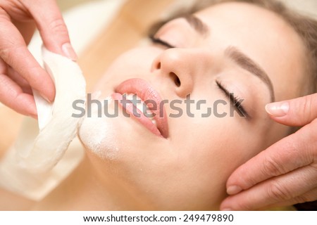 Health spa: close-up of a beautiful relaxing woman having facial massage with a talcom powder
