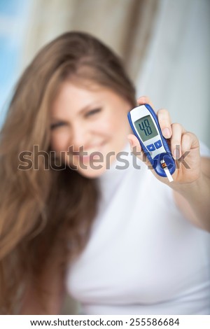Female Diabetic Showing a Glucose Level Finger Blood Test with Good Result . Selective Focus is in the Hand