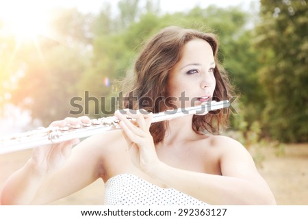 Portrait of Beautiful Young Woman Playing The Silver Flute in the Perfect Sunny Autumn Day