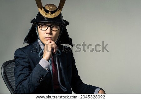 Japanese businessman wearing a samurai's helmet who thinks something. Photo stock © 