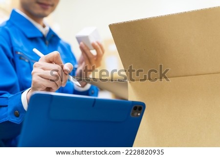 A worker who inspects products and chucks them with a tablet. Foto stock © 