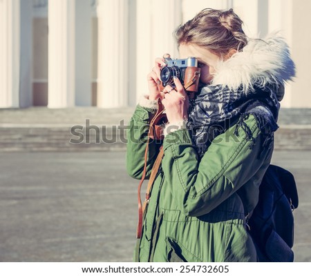 Girl in the green jacket photographs vintage camera outdoors on a sunny spring day
