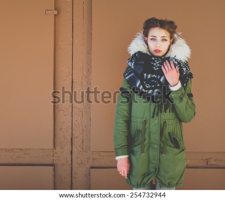 Beautiful unusual girl in a green jacket next to the brown door