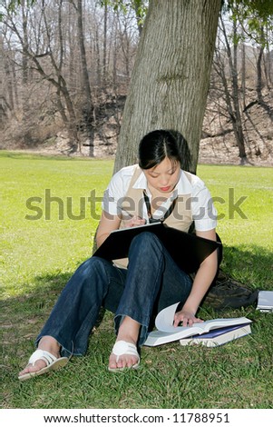 cute asian korean girl outside studying in the park