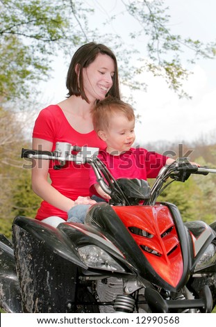 adult female and young male child riding on a four wheel all terrain vehicle in the woods