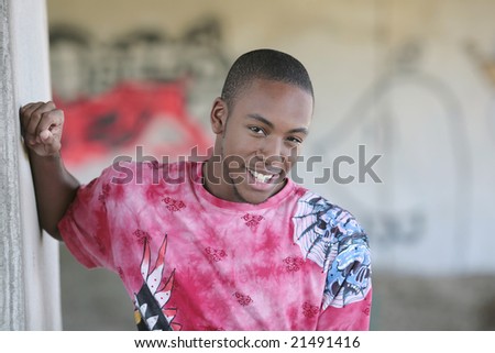 a young African American male model smiling outdoors in front of graffiti