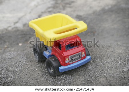 one colorful toy dump truck sitting on rocks outside