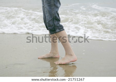 two feet walking along the beach near the water