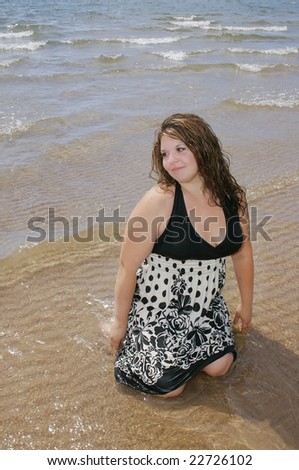one plus size woman kneeling in the shallow ocean water
