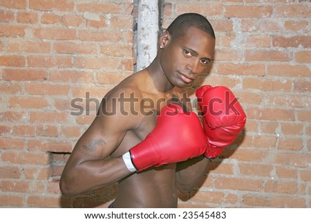 a young black male preparing to fight with boxing gloves in urban scene