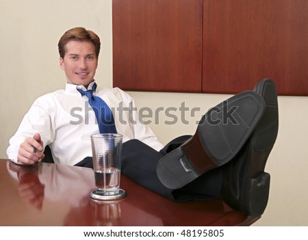 one thirties businessman sitting near a conference room table with his feet up