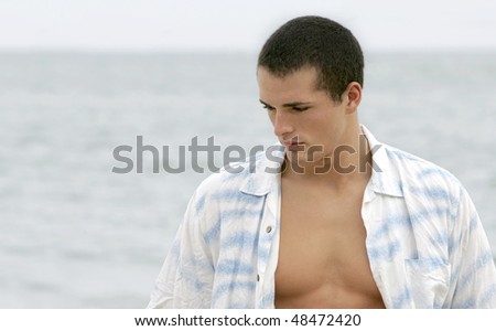 one sad looking alone young man at the beach staring into space