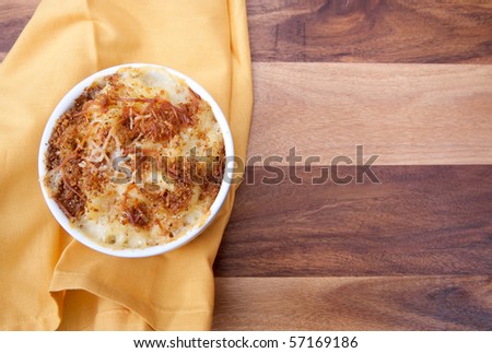 homemade macaroni and cheese in a ramekin with copyspace on a yellow napkin and wood surface