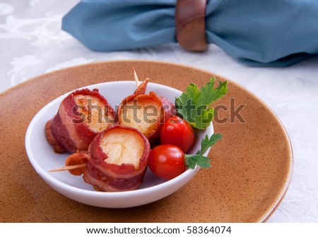 three bacon wrapped scallops in a bowl with tomatoes