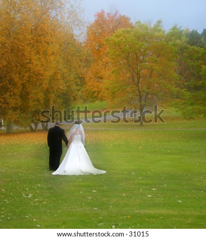 Bride and groom with lots of fall colors around them.
