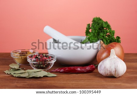 Composition of White mortar and pestle with spice and vegetables on red background