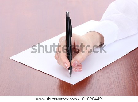 woman hand writing on paper, on wooden table