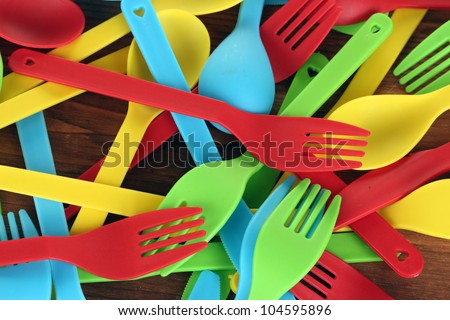 bright plastic disposable tableware on wooden background close-up