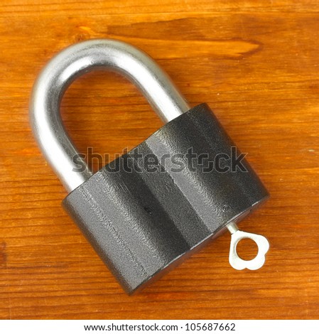 old padlock with key on wooden background close-up