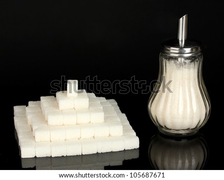 refined sugar in glass sugar bowl isolated on black