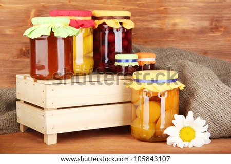 Jars with canned fruit on wooden background