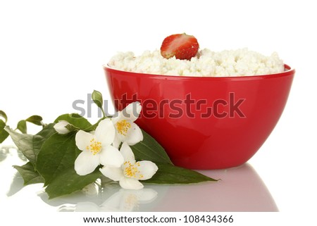 cottage cheese with strawberry in red bowl and flowers on white background close-up