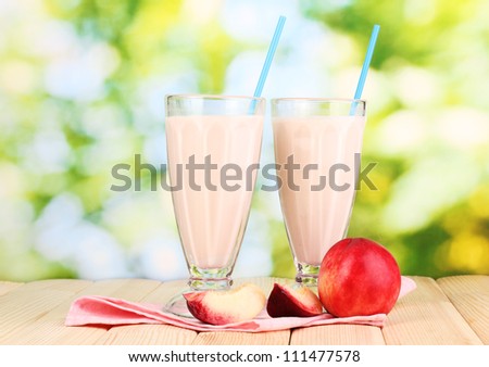 Peach milk shakes on wooden table on bright background