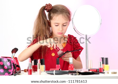 little girl in her mother\'s dress, is trying painting her face