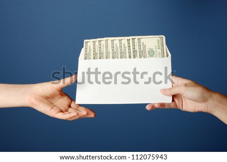 Woman\'s hand passes the envelope with the salary on blue background