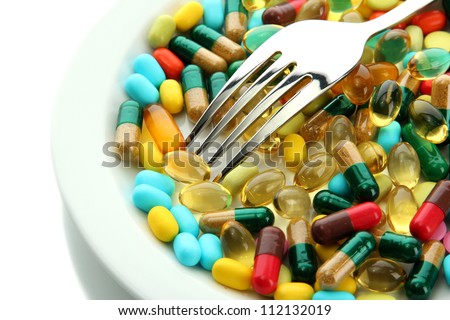 Colorful capsules and pills on plate with fork, isolated on white