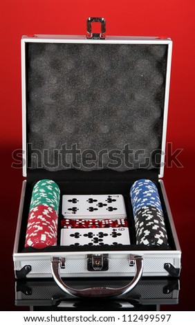 Poker set in metallic case on bright red background