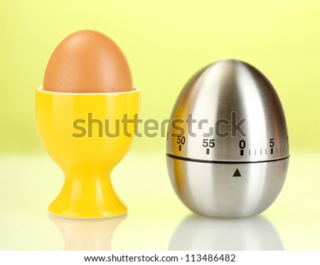 egg timer and egg in orange stand on green background