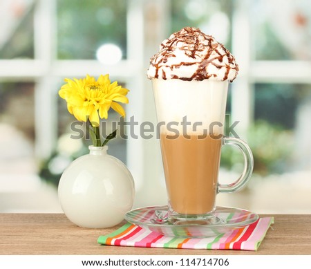 glass of fresh coffee cocktail and vase with flower on wooden table close-up