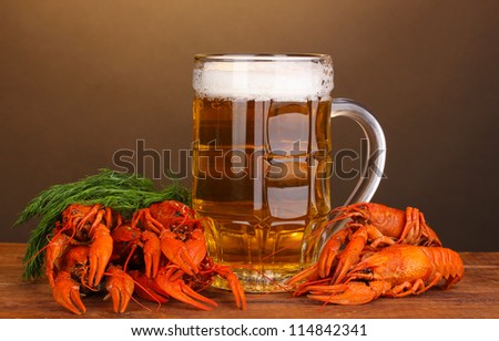 Tasty boiled crayfishes and beer on table on brown background