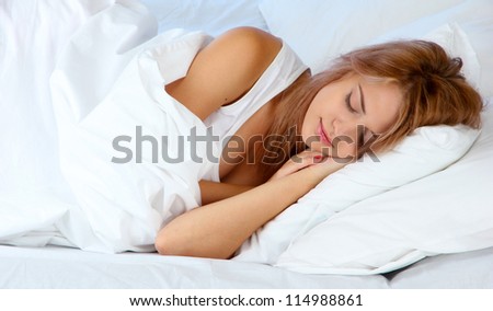 young beautiful woman sleeping on bed on blue background