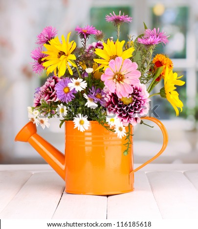 beautiful bouquet of bright flowers in watering can on wooden table
