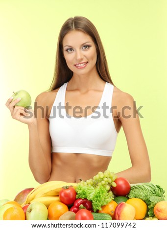 beautiful young woman with fruits and vegetables, on green background