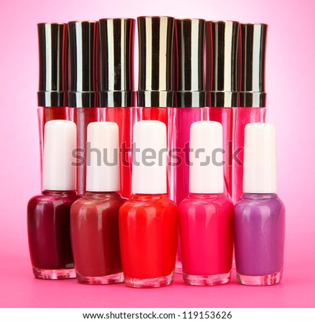 beautiful lip glosses and nail polish bottles, on pink background