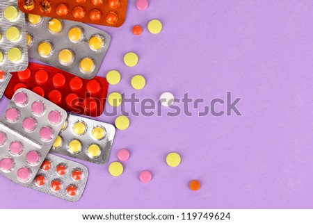 Capsules and pills packed in blisters on purple background
