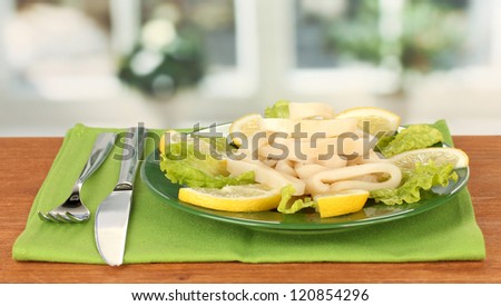 cooked squid rings on lettuce with lemon on the plate close-up