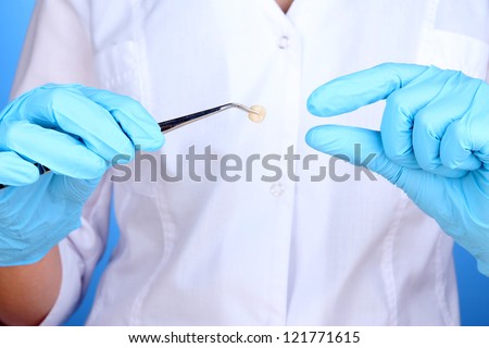 A dentists hands in blue medical gloves with dental tools