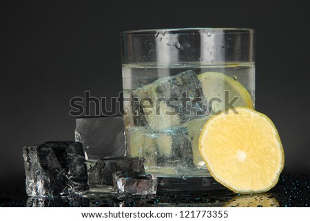 Ice cubes in glass with lemon isolated on black