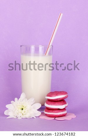 Glass of fresh new milk with cakes on purple background