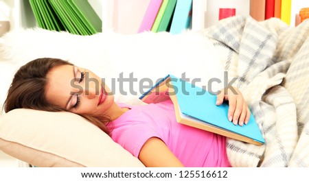 Portrait of female asleep while reading book on couch