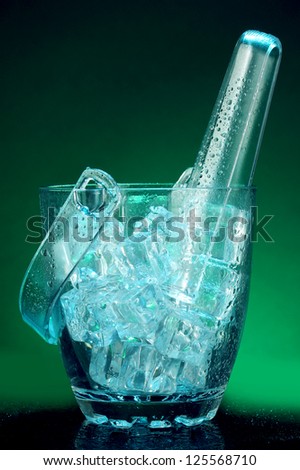 Glass ice bucket on dark green background