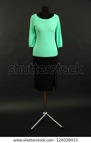 Turquoise blouse and black skirt on mannequin on black background