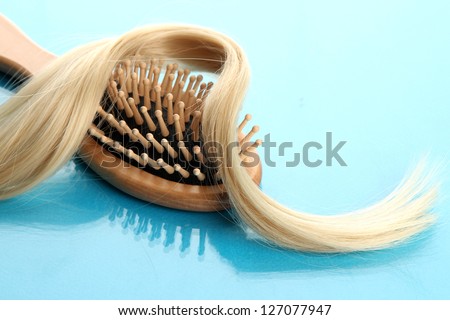 wooden comb brush with hair,  on blue background