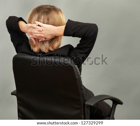 Young beautiful business woman resting on chair on grey background