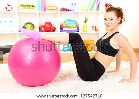 Young woman doing fitness exercises with gym ball at home