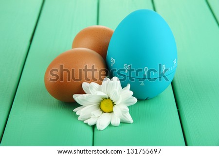 Blue egg timer and eggs, on color  wooden background